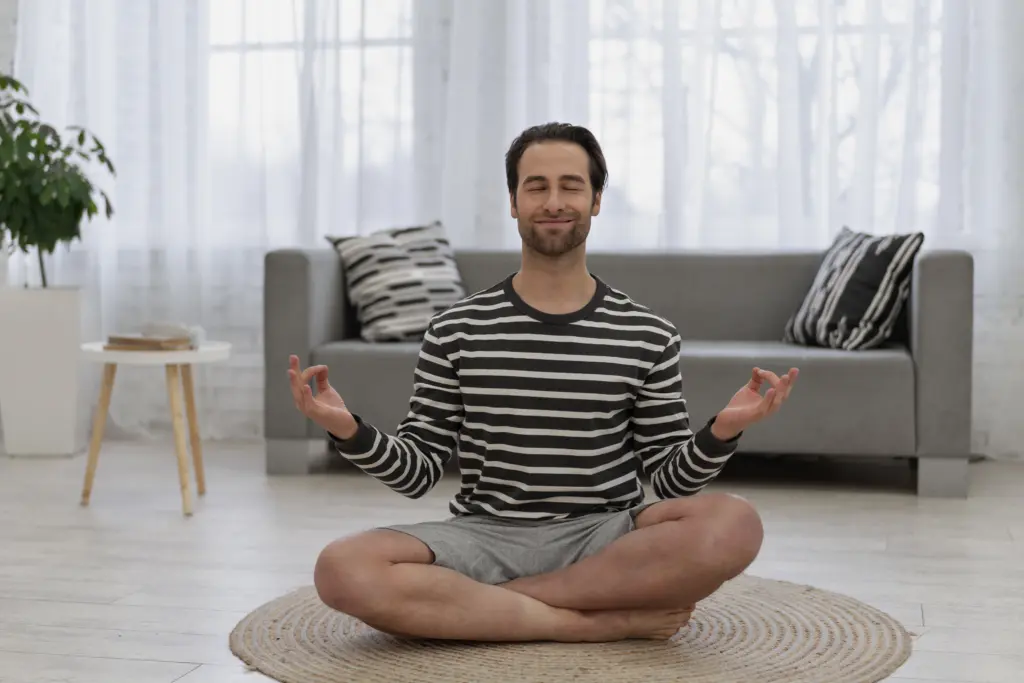 Man mediteert thuis op een kleed in de woonkamer voor ontspanning en mindfulness
